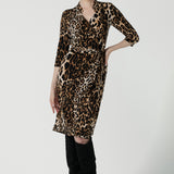 Size 10 woman wears the Jett Dress in Gold Leopard. A functioning wrap dress with a tie waist and mandarin collar. Trending Leopard print. Made in Australia for women size 8 - 24. Petite to plus size fashion.