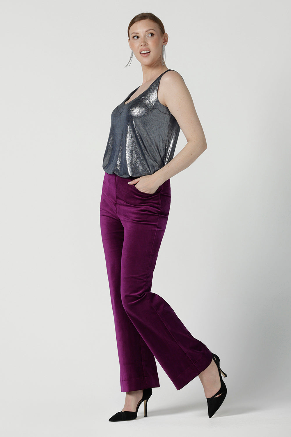 A size 10 woman wears the Eddy Cami in Twilight. A shimmer jersey cami top with wide shoulder straps for bra coverage. Made in shimmer jersey with a high low hem line. Made in Australia for women size 8 - 24. Styled back with the Jonas pant in Megenta.