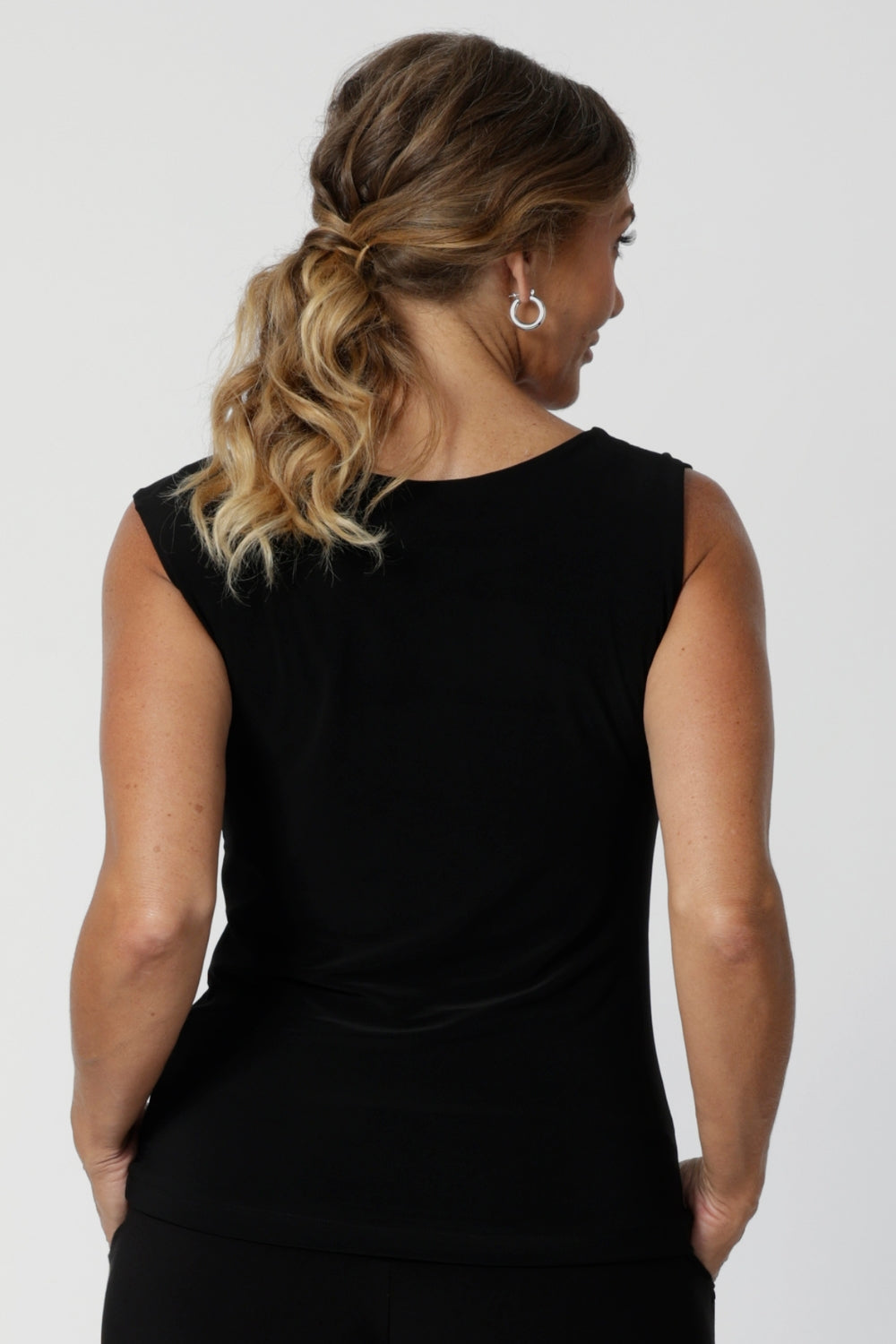 The Jordan Top is the perfect workwear piece, designed with the modern woman in mind. A woman over 40 wears the top with the cowl neckline draped at the back, creating an elegant, effortless effect. This versatile sleeveless top can also be flipped to reveal the boat-neck style, offering a more open and structured silhouette.