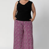 This reversible double-layer top offers two chic styling options: a cowl neckline with a twisted shoulder detail, or a more structured boat-neck look for versatility. Plus size woman wears black reversible top with printed pants and black heels for a possible workwear or eventing look.