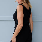 Black reversible top offers two chic styling options, a cowl neckline with a twisted shoulder detail, or a more structured boat-neck look for versatility. Image shows size 12 model wearing her Jordan Top in black with black wide leg pants. 