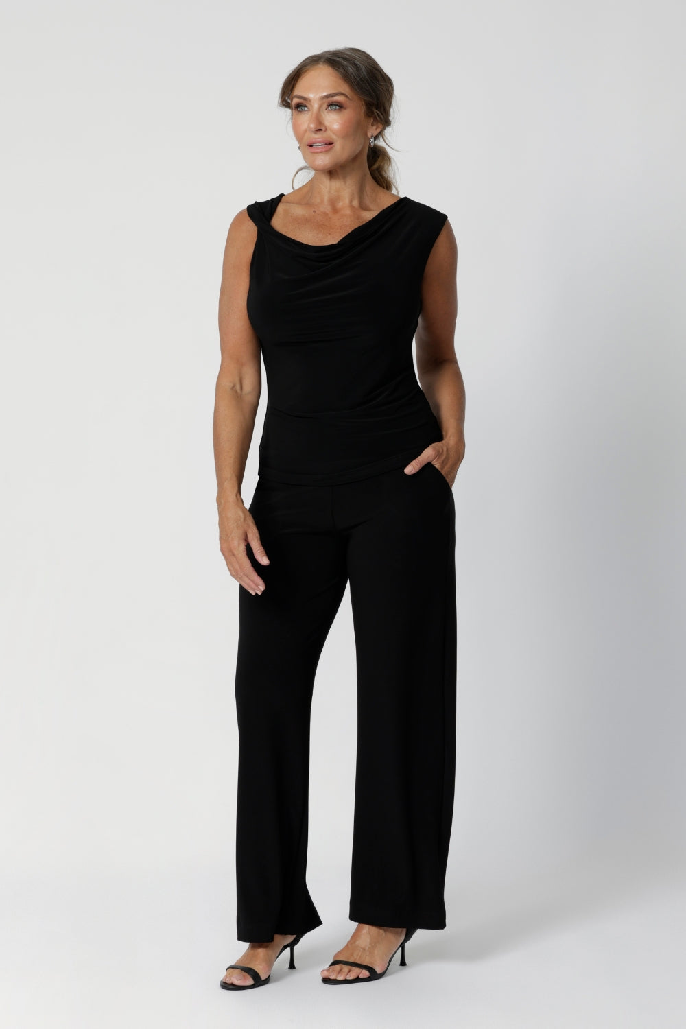 The Jordan Top is the perfect summer workwear piece, designed with the modern woman in mind. A woman over 40 wears the top with the cowl neckline front facing paired back with classic black pants. Available in 3 colourways and in sizes 8-24.