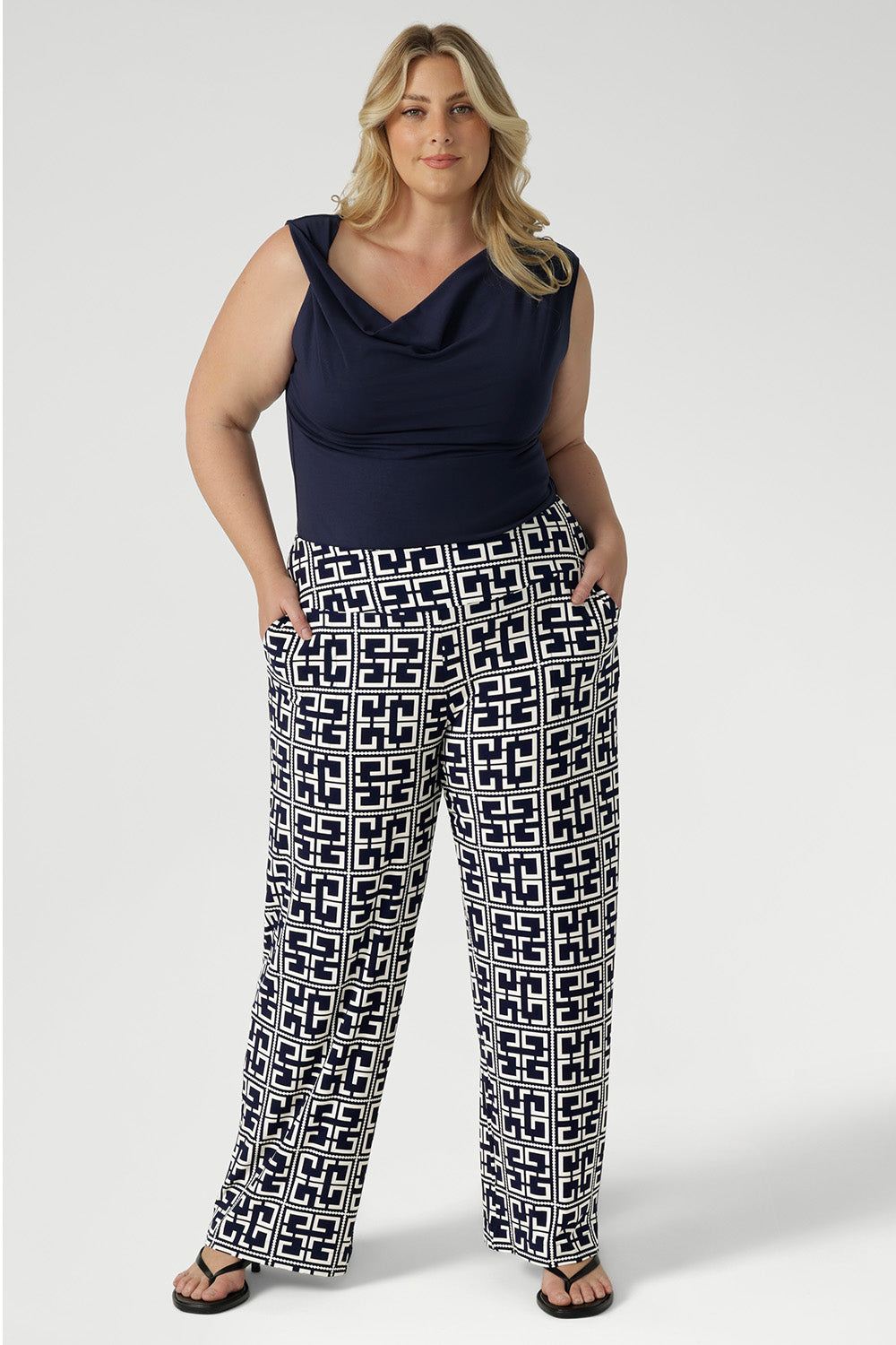 Confident and effortlessly chic, the plus-size woman wearing the Jordan Top in deep indigo denim brings elevated ease to everyday style. Size 18 woman wears her cowl neck top tucked into her new printed Monroe Pants in Ink Olympia. She wears the long length pants.