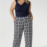 Confident and effortlessly chic, the plus-size woman wearing the Jordan Top in deep indigo denim brings elevated ease to everyday style. Size 18 woman wears her cowl neck top tucked into her new printed Monroe Pants in Ink Olympia. She wears the long length pants.