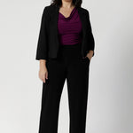 Petite height woman wears magenta coloured top that is reversible under matching black suiting. For a pop of colour that injects chic style into an everyday workwear look. Shop reversible top in 3 different colours and across a range of sizes from 8-24.