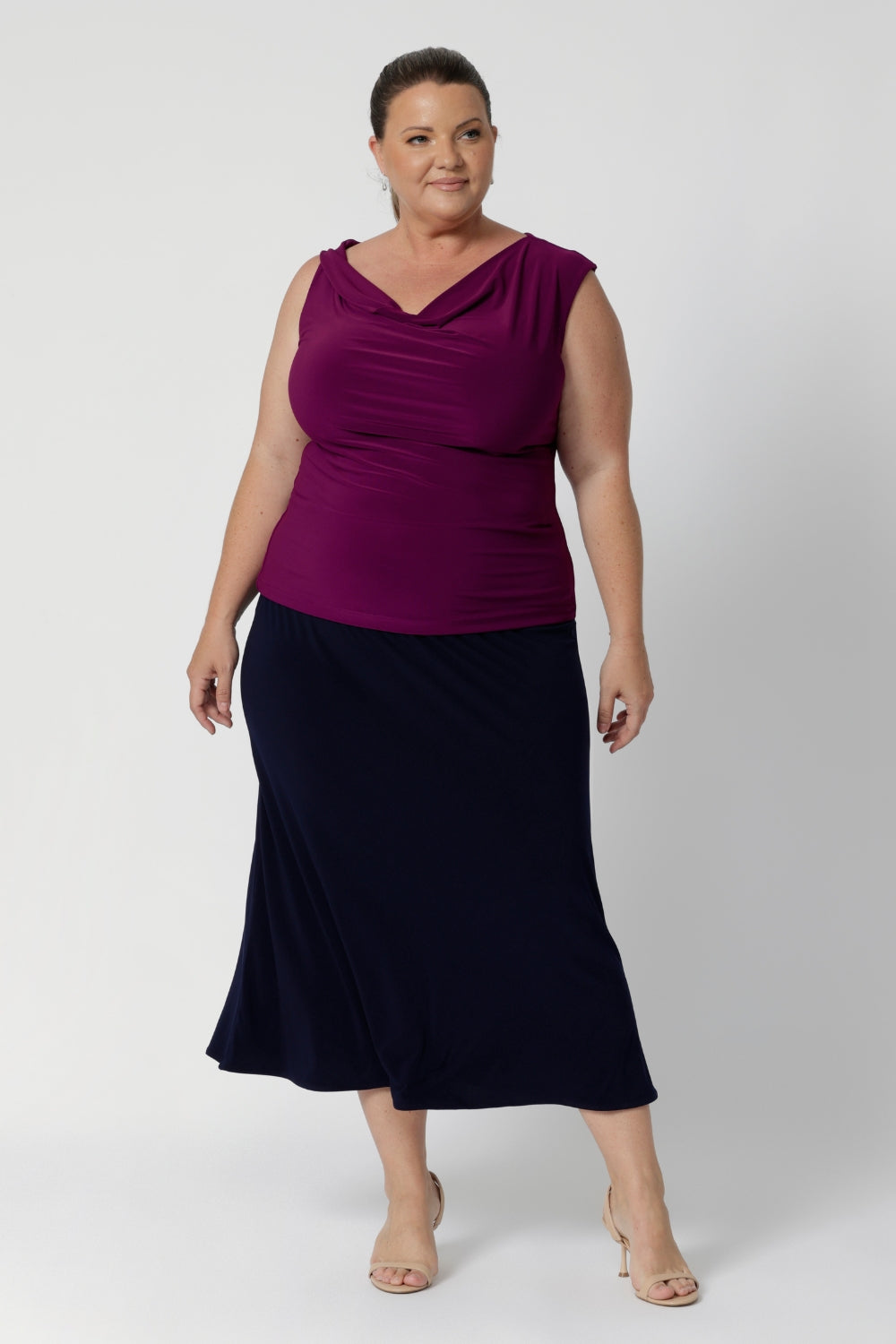 Size 18 woman wears woman's cowl neck top with twist shoulder detail. Reversible top can be worn with a cowl neckline front or boat-neck style for versatility in silhouette. Available online woman's clothing brand Leina & Fleur in sizes 8-24.