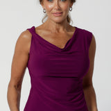 Over 40's women wears reversible double layer top with a cowl neckline and twisted shoulder detail, that can also be worn as a boat-neck top. Versatile workwear top in magenta can be worn with plains and prints. Available in sizes 8-24.