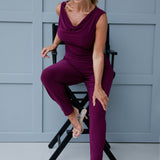 Image shows over 40's woman wearing magenta coloured top with cowl neck front, paired with matching magenta pants for a faux jumpsuit look. Reversible double-layer design can be worn with a cowl neckline front facing or flipped to reveal a boat-neck style for a more open, structured silhouette. 