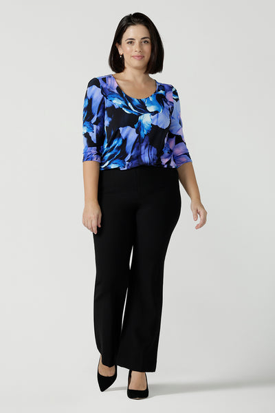 Size 10 woman wears the Jules top in Blue Lily. A Scoop neck style we a 3/4 sleeve. Digitally printed with a blue Lily Print. Size inclusive fashion, made in Australia for women size 8 - 24. Styled back with Black Brett pants. 