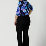 Size 10 woman wears the Jules top in Blue Lily. A Scoop neck style we a 3/4 sleeve. Digitally printed with a blue Lily Print. Size inclusive fashion, made in Australia for women size 8 - 24. Styled back with Black Brett pants.