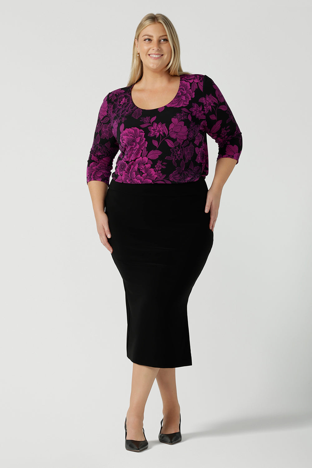 Size 18 woman wears the Jules top in Fuchsia Flora with a scoop neckline and 3/4 sleeves. Comfortable and easy care jersey fabric perfect for work to dinner style. Made in Australia for women size 8 - 24.