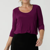 A close up of a size 10 woman wears the Jules top in Magenta. A soft jersey easy care 3/4 sleeve top ion rich purple magenta colour. Scoop neckline and made in Australia for women size 8 - 24. Styled back with an Andi Tube skirt in black.