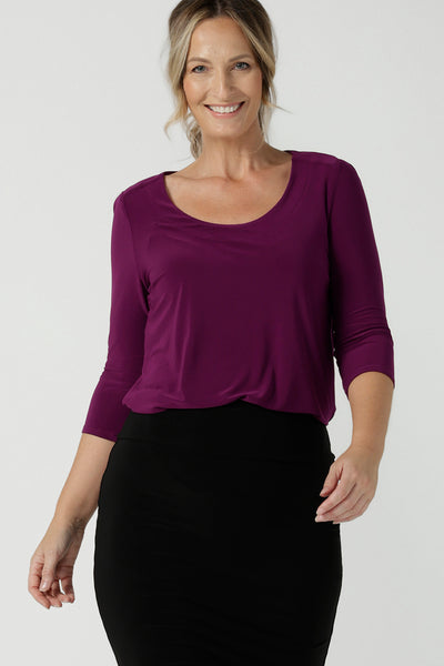 A close up of a size 10 woman wears the Jules top in Magenta. A soft jersey easy care 3/4 sleeve top ion rich purple magenta colour. Scoop neckline and made in Australia for women size 8 - 24. Styled back with an Andi Tube skirt in black.