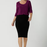 A size 10 woman wears the Jules top in Magenta. A soft jersey easy care 3/4 sleeve top ion rich purple magenta colour. Scoop neckline and made in Australia for women size 8 - 24. Styled back with an Andi Tube skirt in black.