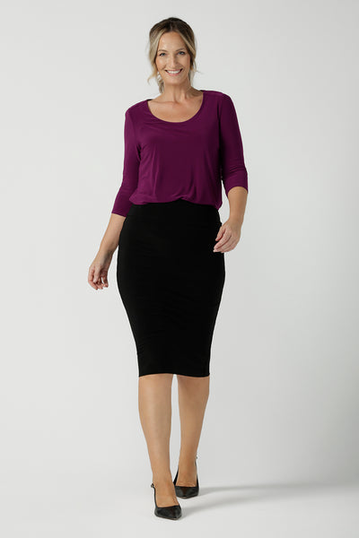 A size 10 woman wears the Jules top in Magenta. A soft jersey easy care 3/4 sleeve top ion rich purple magenta colour. Scoop neckline and made in Australia for women size 8 - 24. Styled back with an Andi Tube skirt in black.