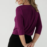 Back view of a size 10 woman wears the Jules top in Magenta. A soft jersey easy care 3/4 sleeve top ion rich purple magenta colour. Scoop neckline and made in Australia for women size 8 - 24. Styled back with an Andi Tube skirt in black.