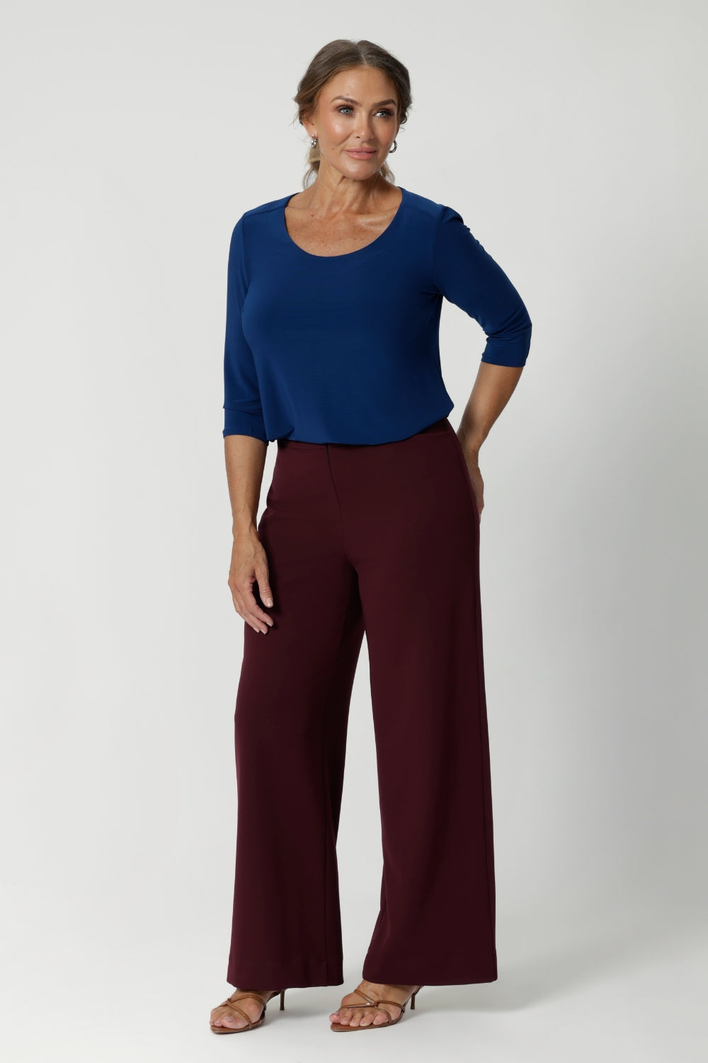 Image shows over 40's woman wearing a 
women's basic tailored shirt. Designed for both workwear and weekend wear. Crafted from a deep blue dry-touch jersey fabric, this top offers a soft stretch that moves with you, ensuring all-day comfort without compromising on style. Easy care workwear top provides a polished finish with it's wrinkle resistant qualities. Available in sizes 8-24, online at Leina & Fleur. 