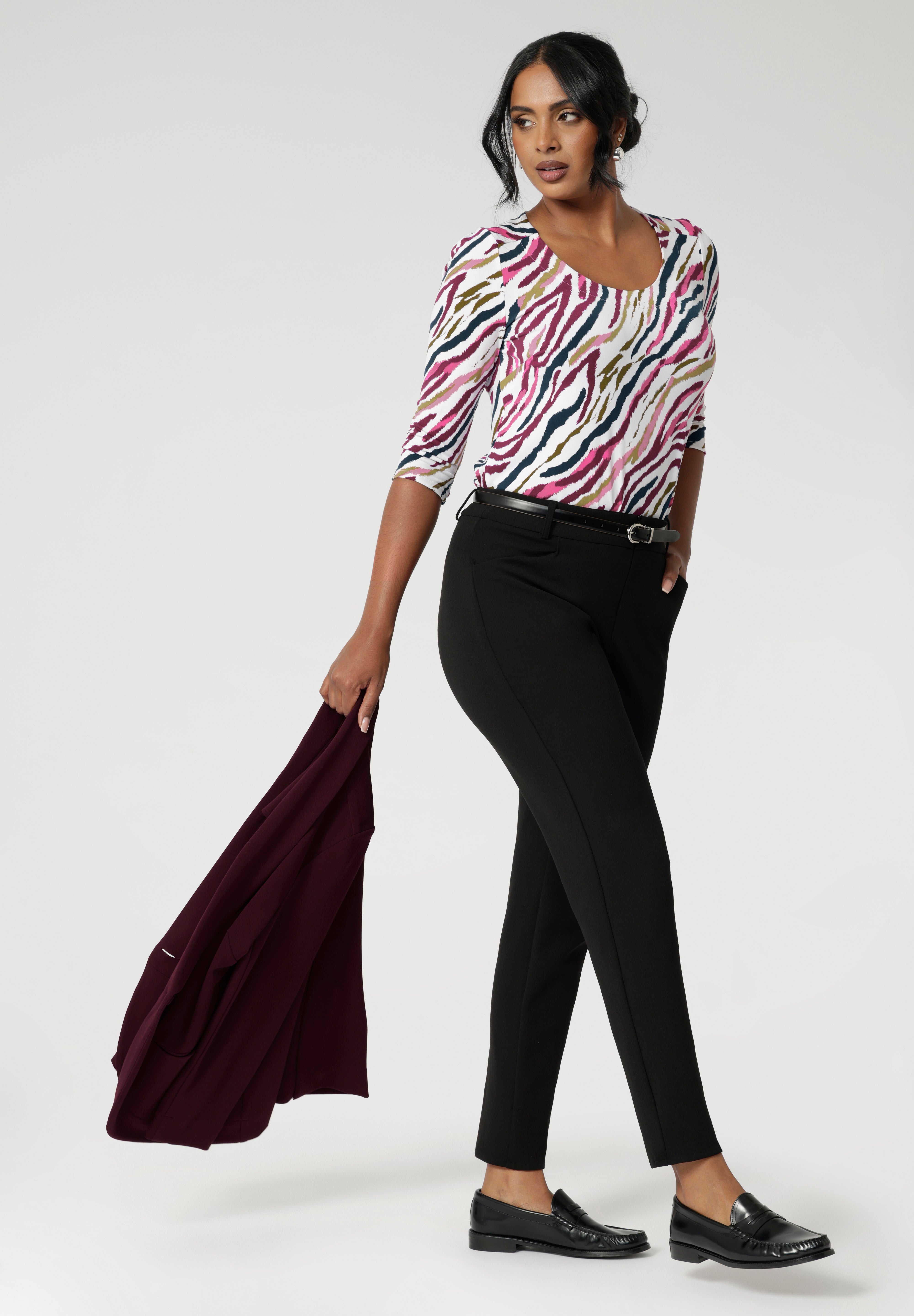 Size 10 woman wears printed scoop neck top with black tapered pants and wine coloured blazer. The vibrant Rainbow Zebra print, featuring shades of pink, taupe, and navy, adds a unique, eye-catching touch to a classic workwear look. Available in sizes 8-24.