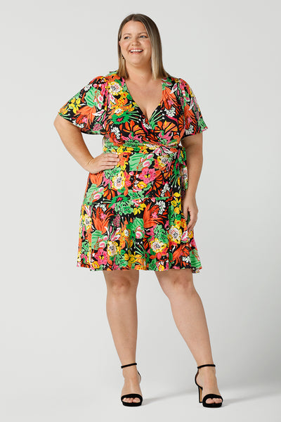  A size 18 curvy woman wears a colourful jersey wrap dress in the Cancun print. A petite-height-friendly wrap dress with flutter sleeves and playful ruffle hem, twirl away the summer in the Julie Dress in Cancun. Made in Australia for sizes 8 -24