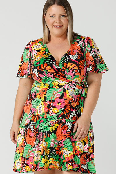  Close up of a size 18 curvy woman wears a colourful jersey wrap dress in the Cancun print. A petite-height-friendly wrap dress with flutter sleeves and playful ruffle hem, twirl away the summer in the Julie Dress in Cancun. Made in Australia for sizes 8 -24