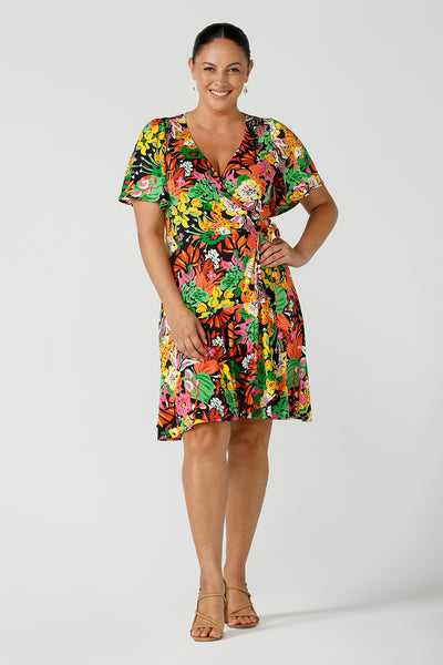 A size 12 curvy woman wears a colourful jersey wrap dress in the Cancun print. A petite-height-friendly wrap dress with flutter sleeves and playful ruffle hem, twirl away the summer in the Julie Dress in Cancun. Made in Australia for sizes 8 -24