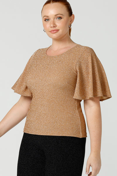A size 12, fuller figure woman wears a sparkly honey glam top with flutter. Sleeves. Made in Australia by Australian and New Zealand women's clothing company, this shimmer jersey top wears well with evening and occasion-wear skirts, pants and suit jackets.