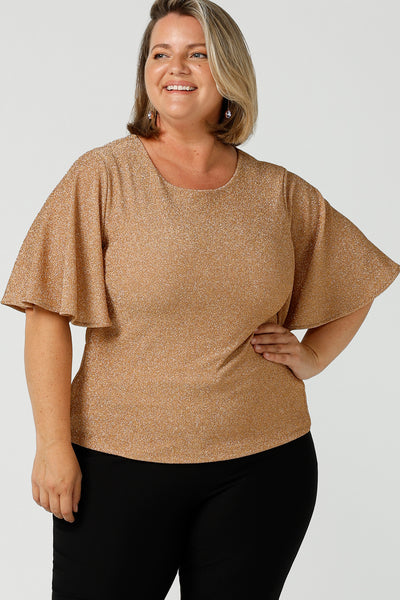 A size 18, fuller figure woman wears a sparkly honey glam top with flutter. Sleeves. Made in Australia by Australian and New Zealand women's clothing company, this shimmer jersey top wears well with evening and occasion-wear skirts, pants and suit jackets.