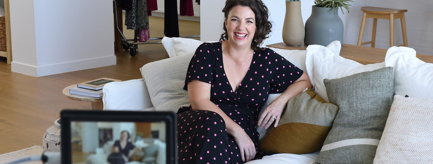 womens clothing australia - model wears a beautifully fitted black jumpsuit casually on the coach. Jumpsuit features comfortable sleeves and pink polkadots 