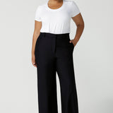 A good full length trouser for plus size women, these Navy blue, tailored wide leg pants are shown on a size 18, curvy woman. Worn with a short sleeve, white bamboo jersey top, these elegant pants wear for work as smart casual wear. Shop made in Australia trousers for women online at women's clothing brand Leina & Fleur.