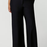 Close up of good full length trousers for plus size women, these Navy blue, tailored wide leg pants are shown on a size 18, curvy woman. Worn with a short sleeve, white bamboo jersey top, these elegant pants wear for work as smart casual wear. Shop made in Australia trousers for women online at women's clothing brand Leina & Fleur.