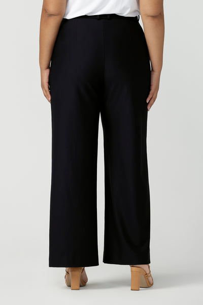 Back view of a good full length trouser for plus size women, these Navy blue, tailored wide leg pants are shown on a size 18, curvy woman. Worn with a short sleeve, white bamboo jersey top, these elegant pants wear for work as smart casual wear. Shop made in Australia trousers for women online at women's clothing brand Leina & Fleur.