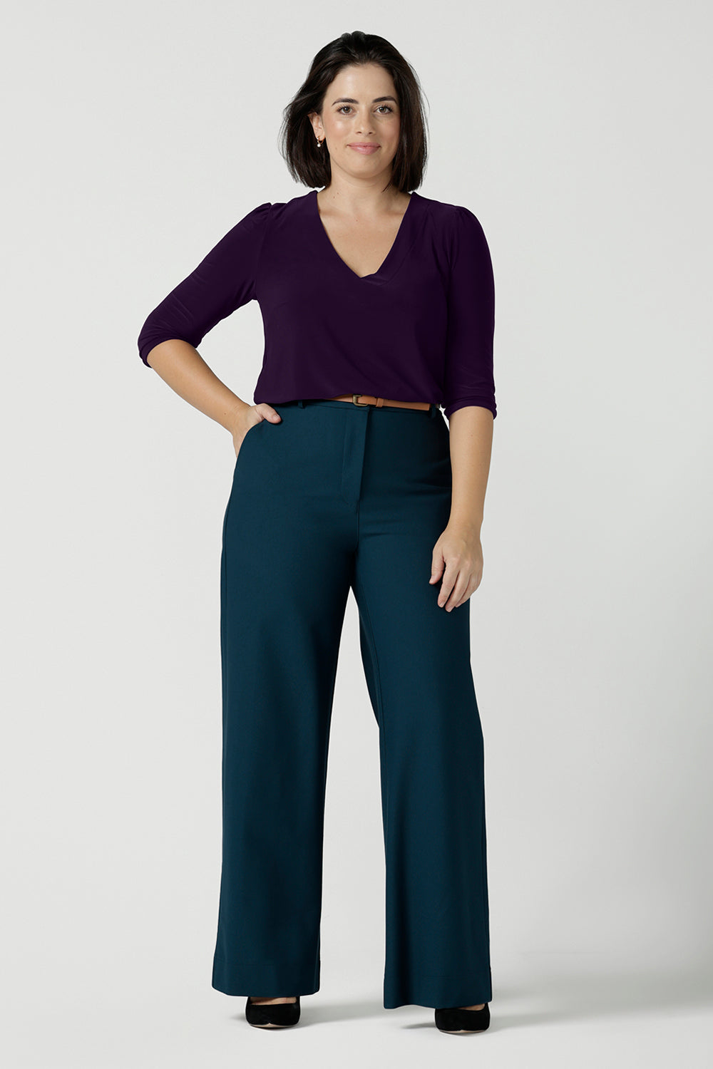 A size 10 woman wears the Yael pant in Petrol. A high waist tailored pant with tailoring elements like side pockets, zip front and belt loops. Full length wide leg pant suitable for comfortable workwear with a statement Petrol colour. Styled back with Vida top in Amethyst. Made in Australia for women size 8 - 24.