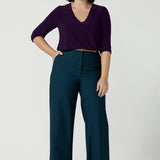 A size 10 woman wears the Yael pant in Petrol. A high waist tailored pant with tailoring elements like side pockets, zip front and belt loops. Full length wide leg pant suitable for comfortable workwear with a statement Petrol colour. Styled back with Vida top in Amethyst. Made in Australia for women size 8 - 24.