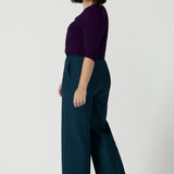 Back view of a size 10 woman wears the Yael pant in Petrol. A high waist tailored pant with tailoring elements like side pockets, zip front and belt loops. Full length wide leg pant suitable for comfortable workwear with a statement Petrol colour. Styled back with Vida top in Amethyst. Made in Australia for women size 8 - 24.