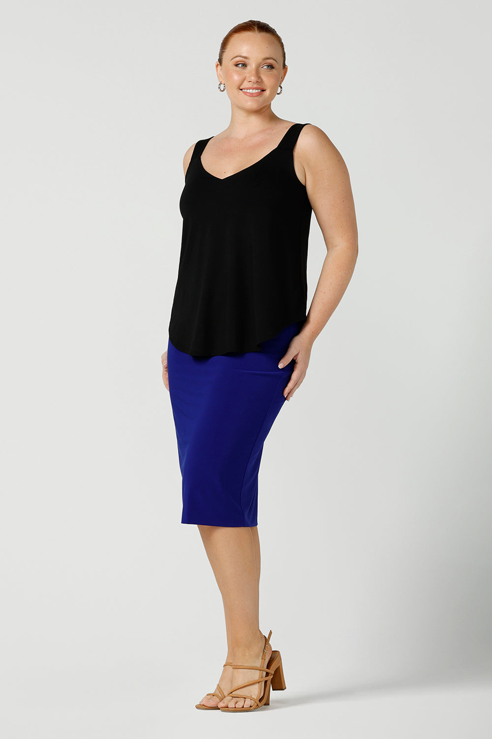a size 12, curvy woman wears a bamboo cami with a cobalt blue fitted tube skirt. In black bamboo jersey, this top is a good addition to your capsule wardrobe for weekend wear, work and travel. Shop Australian-made dresses online is sizes 8 to 24.