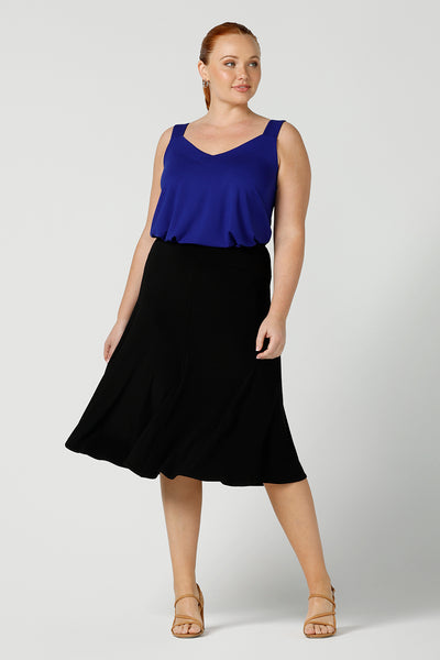 a size 12, curvy woman wears a bamboo cami with a black midi skirt. In cobalt blue bamboo jersey, this top is a good addition to your capsule wardrobe for weekend wear, work and travel. Shop Australian-made dresses online is sizes 8 to 24.