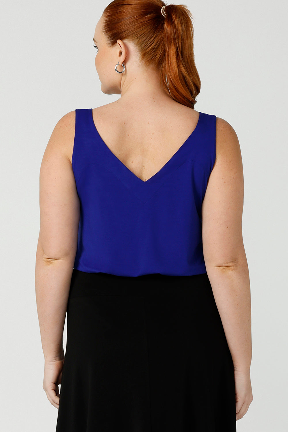 Back view of a size 12, curvy woman wears a bamboo cami. In cobalt blue bamboo jersey, this top is a good addition to your capsule wardrobe for weekend wear, work and travel. Shop Australian-made dresses online is sizes 8 to 24.