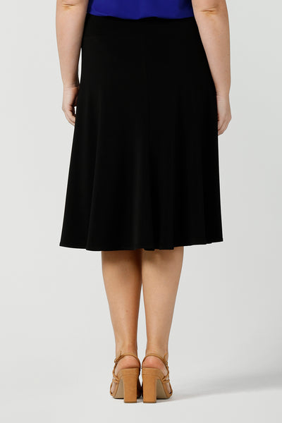 Back view of a black skirt by Australian made women's clothing brand, Leina & Fleur. This knee length, A-line skirt falls softly in black jersey. A comfortable skirt for petite to plus size office wear, this skirt is shown on a size 12, curvy woman. A good black skirt for your capsule wardrobe, shop skirts at Leina & Fleur's online clothing boutique Australia.