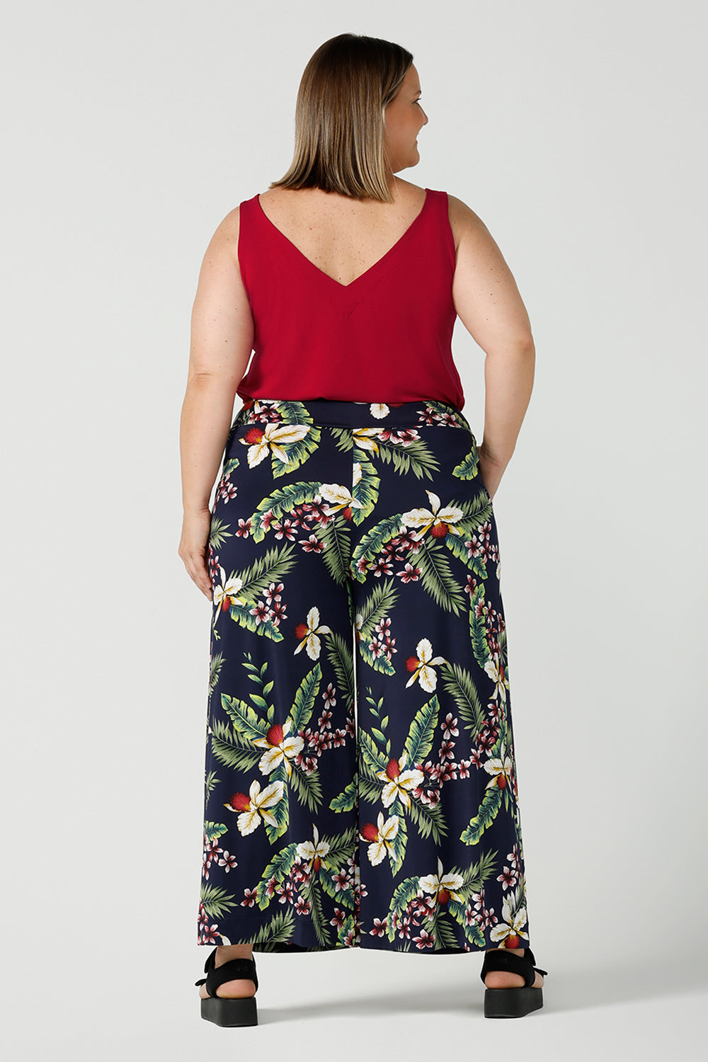 Back view of a size 18 curvy and happy woman wears a wide leg dany culotte in in Merriment back with a red cami top. The perfect comfortable Christmas outfit. Made in Australia for women size 8-24.