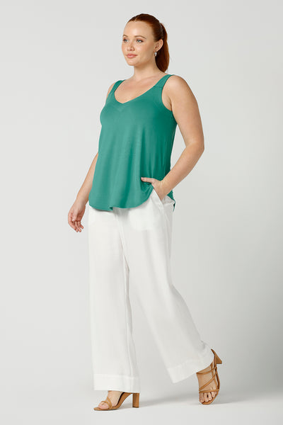 a size 12, fuller figure woman wears a bamboo cami with white woven pants. In jade green bamboo jersey, this top is a good addition to your capsule wardrobe for weekend wear, work and travel. Shop Australian-made dresses online is sizes 8 to 24.