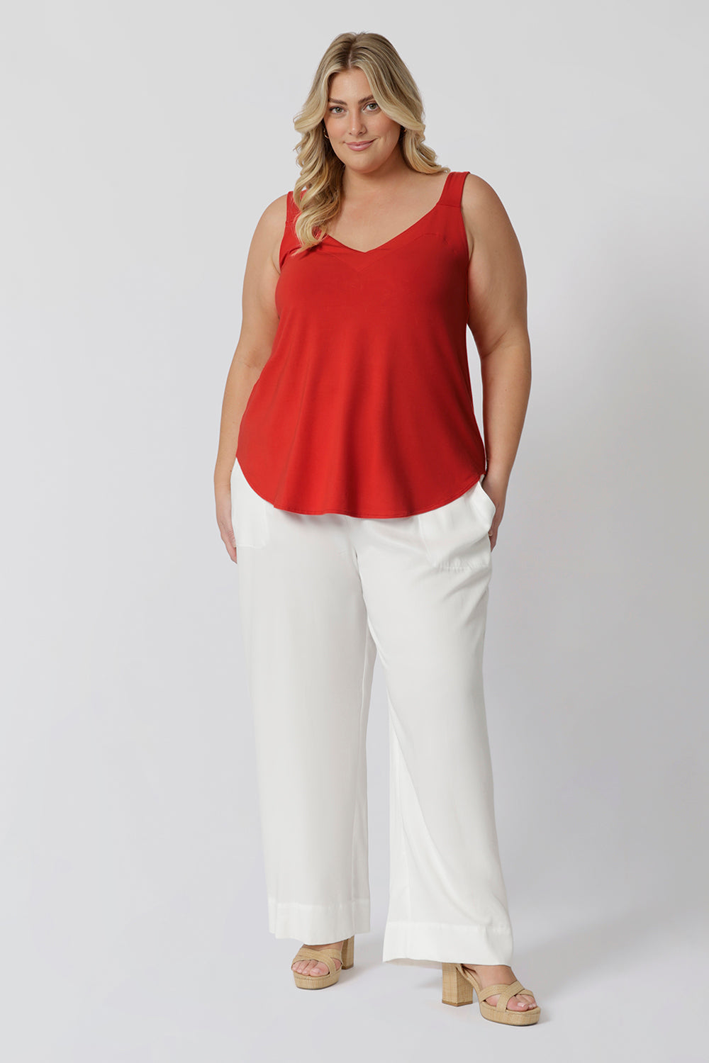 Plus sized woman wears tangerine coloured cami paired back with white pants for a perfect summer day look. The cami features a flattering V-shaped neckline both in the front and back, adding a touch of feminine elegance while offering an easy, breezy fit. Clothing brand Leina & Fleur stock this bamboo cami in sizes 8-24.