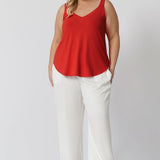 Plus sized woman wears tangerine coloured cami paired back with white pants for a perfect summer day look. The cami features a flattering V-shaped neckline both in the front and back, adding a touch of feminine elegance while offering an easy, breezy fit. Clothing brand Leina & Fleur stock this bamboo cami in sizes 8-24.