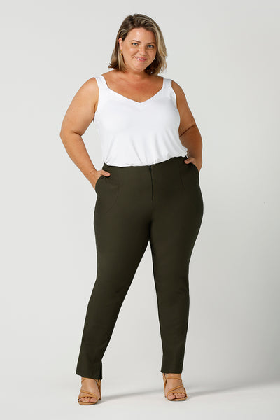 In olive green, these slim leg women's pants are great professional work and office wear trousers. Made in Australia by affordable, ethical clothing brand, Leina & Fleur this stretch pants are worn with a white cami top in bamboo jersey and shown on a size 18, plus size woman. Shop ladies clothing online in petite to plus sizes at Leina & Fleur's online boutique. 