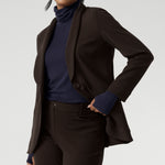Size 10 model wears navy long-sleeved top featuring high turtleneck for added comfort and warmth. Crafted from lightweight, warm tencel wool fabric. Model pairs her wool top with brown suiting for an elevated back to work outfit.