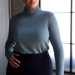 Introducing the Kean high turtleneck top from the Light Layers collection, a stylish and functional piece designed to elevate your wardrobe as the seasons cool. This long-sleeved top features convenient thumb holes for added comfort and warmth. Made from a blend of stretchy Tencel wool fabric, it offers both flexibility and coziness, making it the perfect layering piece for cooler weather.