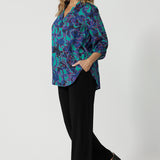 Full body front image of an over 40 year old average height woman, wearing a collared light weight shirt with fabric colours aqua, navy and pink. Shirt has 3/4 sleeves, v neck and collar. This casual shirt is breathable and Australian made. Made by woman in Australia and New Zealand. Leina and Fleur is a woman’s clothing brand that has sizes ranging from 8 to 24 including plus sizes and petite sizes. 