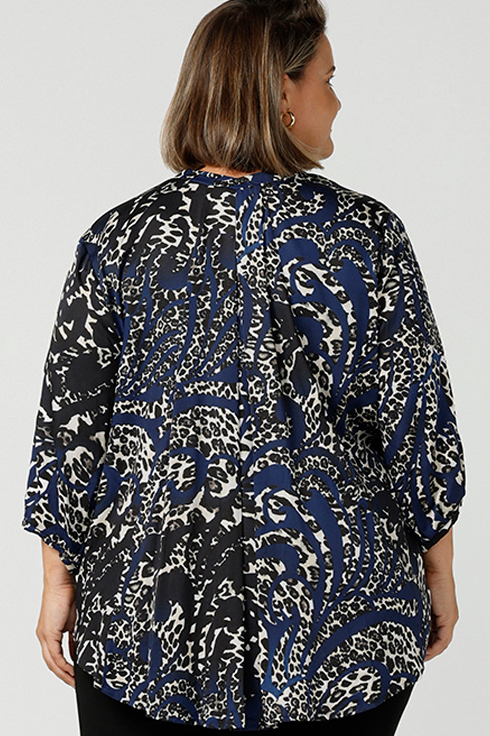 Back view of A curvy size 16  woman wearing an animal print woven top with a high-low hem. This lightweight top is comfortable for your everyday workwear, casual and travel capsule wardrobe. Shop this Australian-made shirt online in sizes 8 to 24, petite to plus sizes.