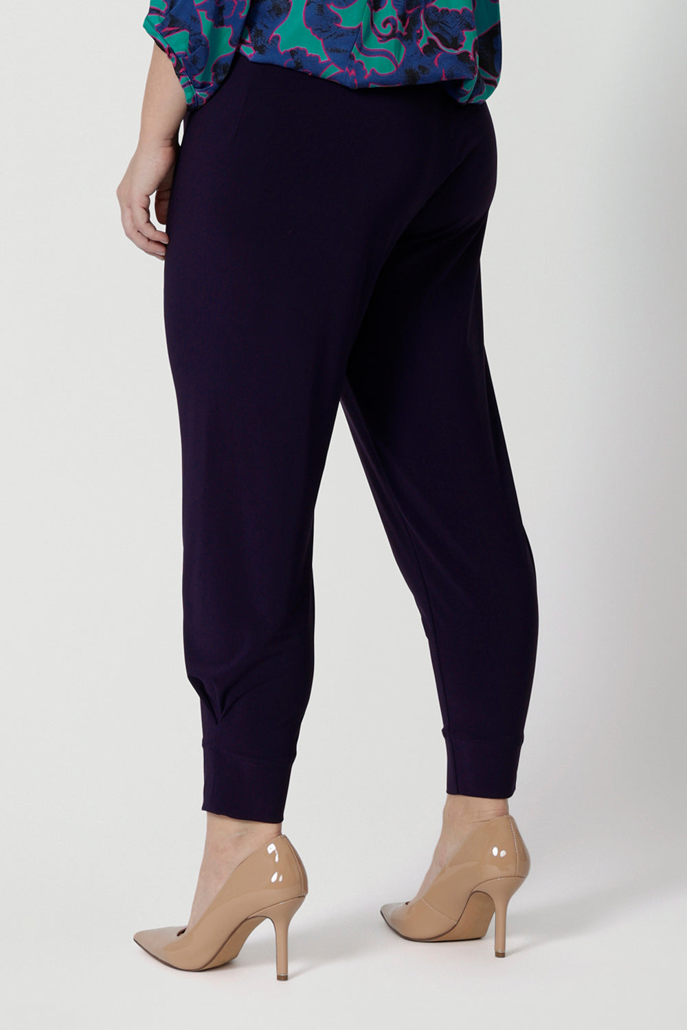 Back view of a good pant for petite women, the Indi Pant in Amethyst is worn with an oversized, 3/4 sleeve blouse. A pull-on pant in stretch jersey, these cropped length trousers make comfortable travel pants. Here, these purple pants are styled for evening and going out wear. 