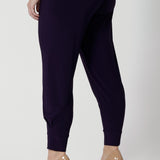 Back view of a good pant for petite women, the Indi Pant in Amethyst is worn with an oversized, 3/4 sleeve blouse. A pull-on pant in stretch jersey, these cropped length trousers make comfortable travel pants. Here, these purple pants are styled for evening and going out wear. 