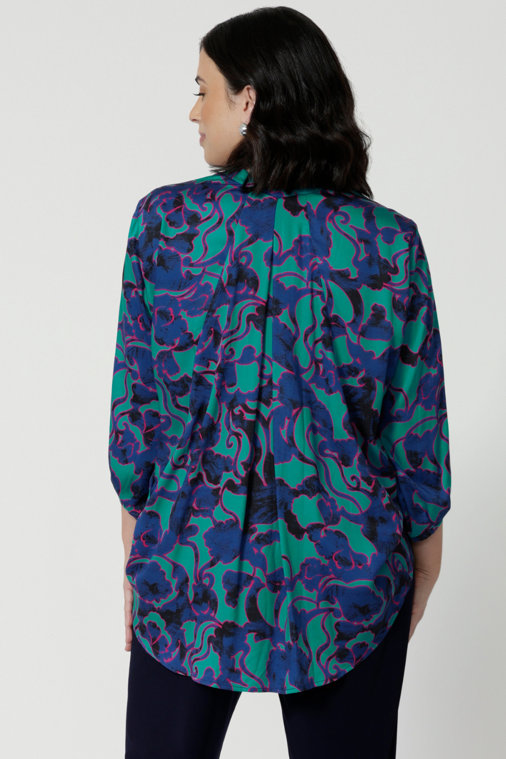 Back view of petite woman wearing a breathable fabric shirt made of satin rayon. Abstract pattern shirt has many colours such as aqua, pink and cobolt blues. This comfortable shirt is Australian made by Australian and New Zealand women. Leina & Fleur is a woman’s clothing label that stocks sizes from 8 to 24. Shop this comfortable blouse in plus size and petite sizes. 